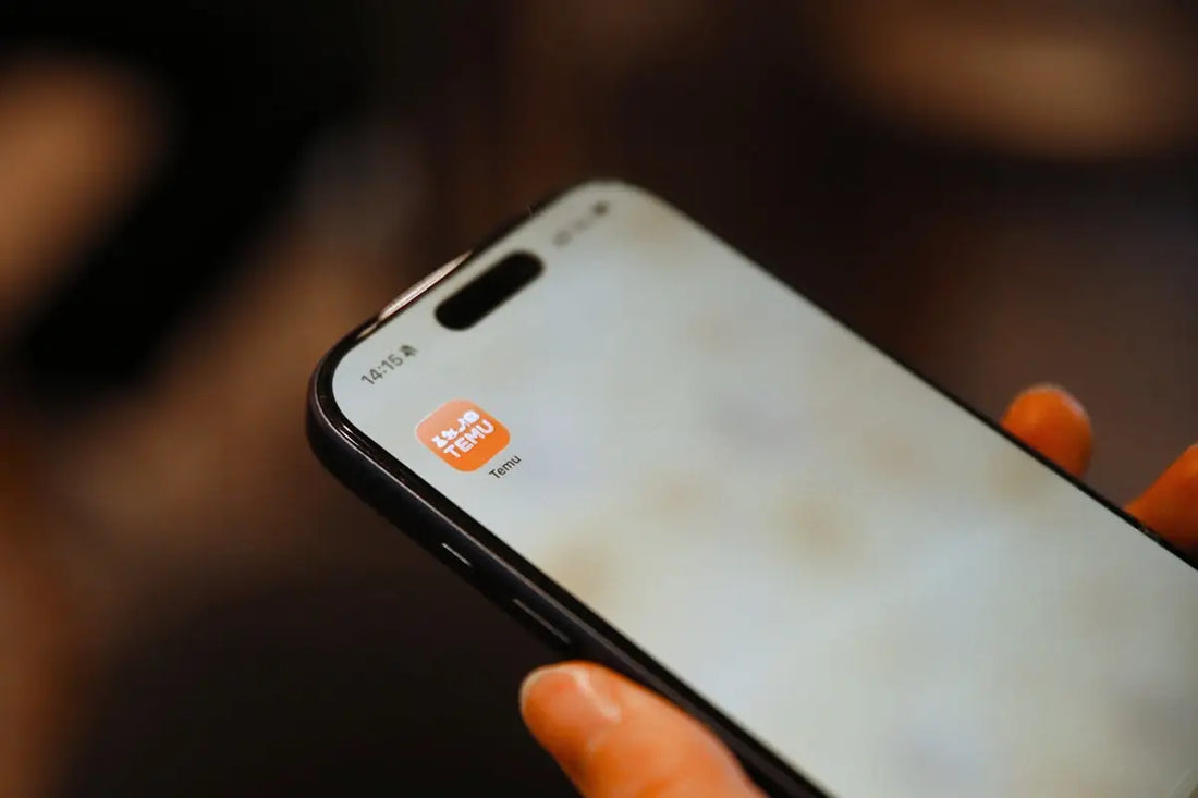 A black iPhone with a white screen showing an orange tinmu app icon for finding deals on trending products at Arba Global