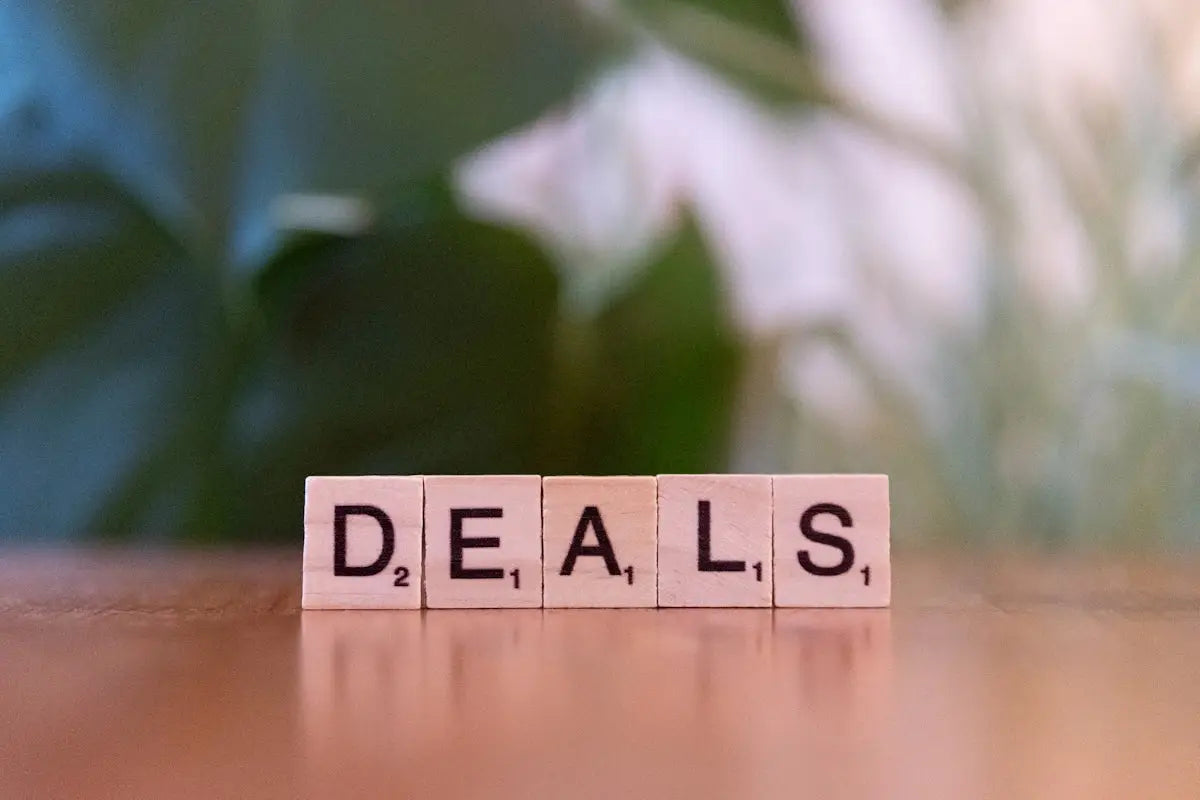 Light beige wooden scrabble tiles spelling deals with black lettering for online tech and fashion deals article.