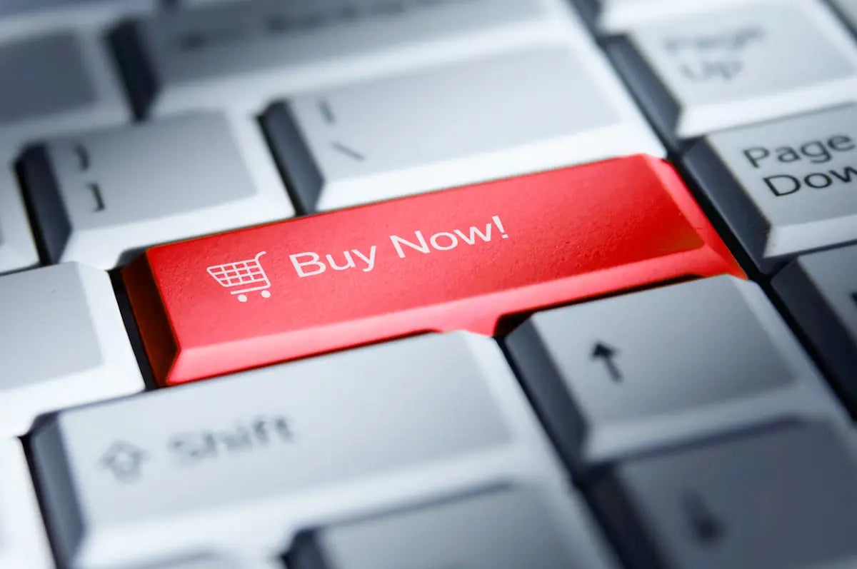 A vibrant red buy now key with a white shopping cart icon on a gray keyboard for affordable tech gadgets.