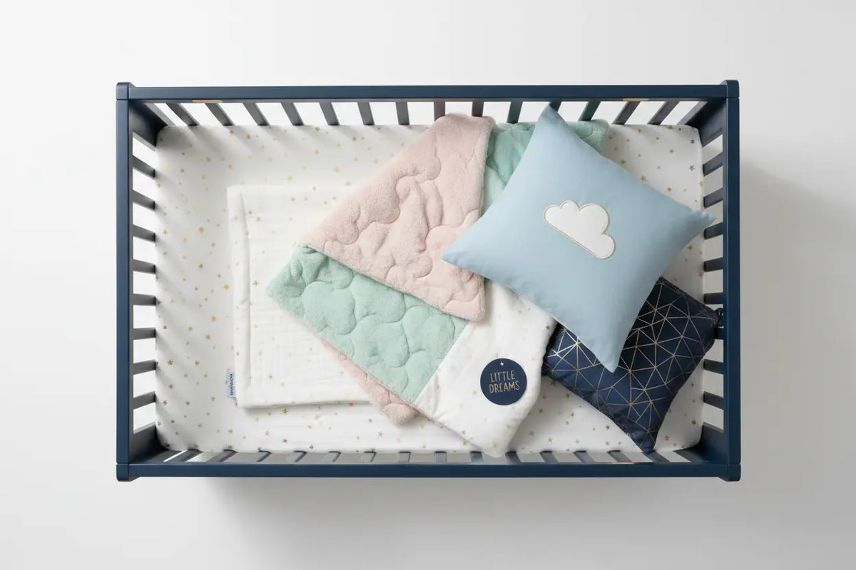 Pastel-colored quilted baby bedding set with cloud and geometric pattern pillows in pink, mint green, blue, and navy