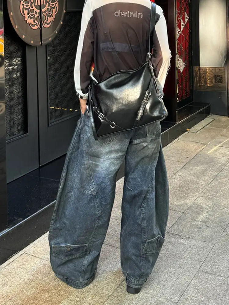 Schwarze Ledertasche im Crossbody-Stil mit silberner Beschlägen und vorderem Reißverschlussverschluss, kombiniert mit Jeans mit Destroyed Wide-Leg im Vintage-Denim.