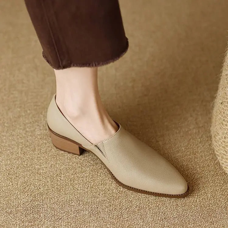 Beige leather slip-on women’s loafers with a low block heel, square toe, and stitched detailing.