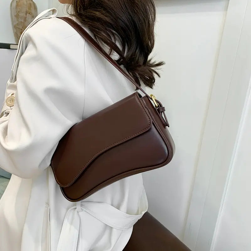 Brown leather messenger bag minimalist crossbody organ bag with sleek design and gold-tone hardware.
