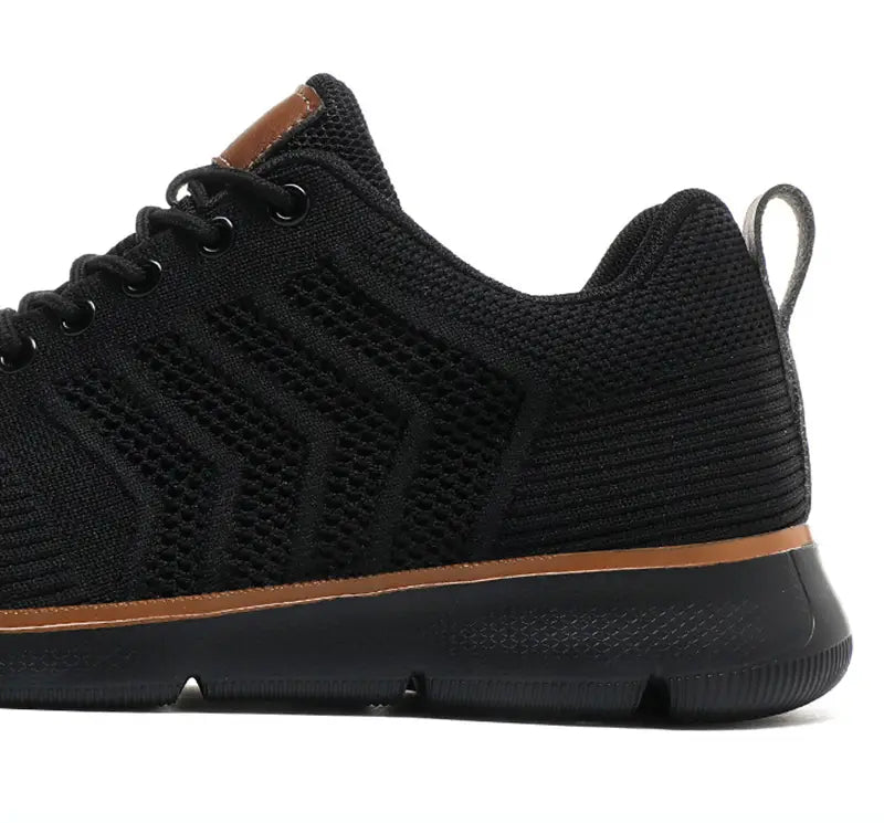 black mesh sneaker for men with tan accents on the heel tab and midsole shown from the back side for casual flying woven shoes.