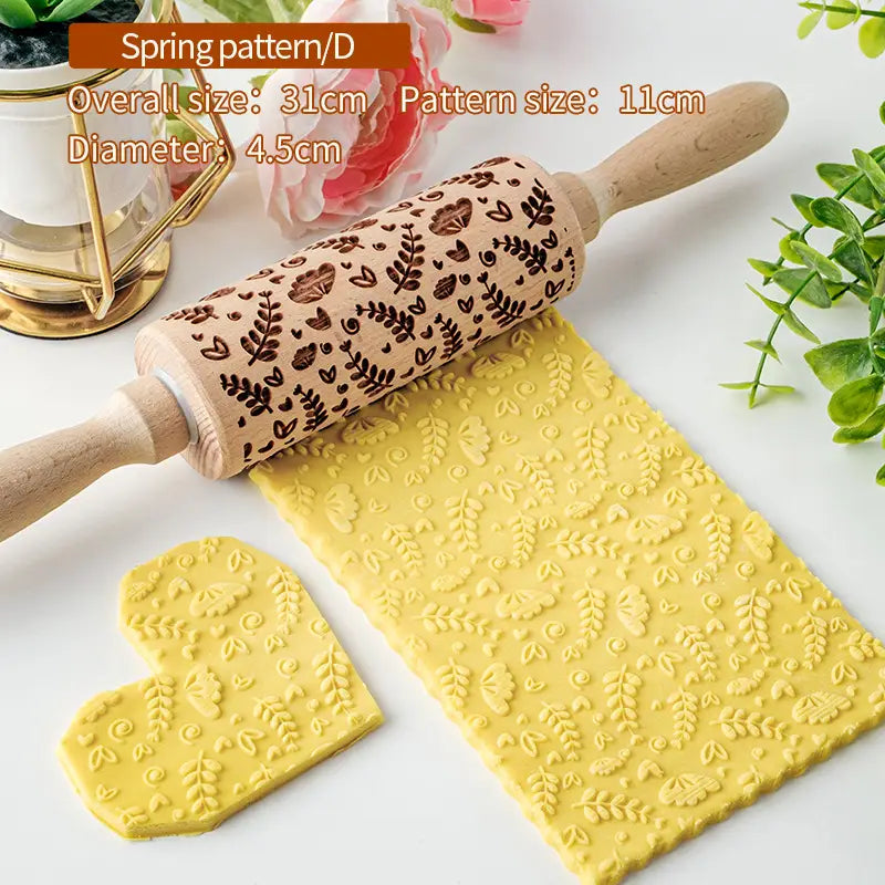 Un rouleau à pâtisserie en bois à poignées en bois clair, présentant un motif printanier sombre brun de feuilles et de cœurs gravé sur du bois de hêtre pour une cuisson en relief florale.