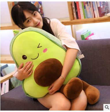 a plush avocado-shaped pillow for kids featuring a soft green body, a brown pit, and a smiling face designed as a soft fruit toy.
