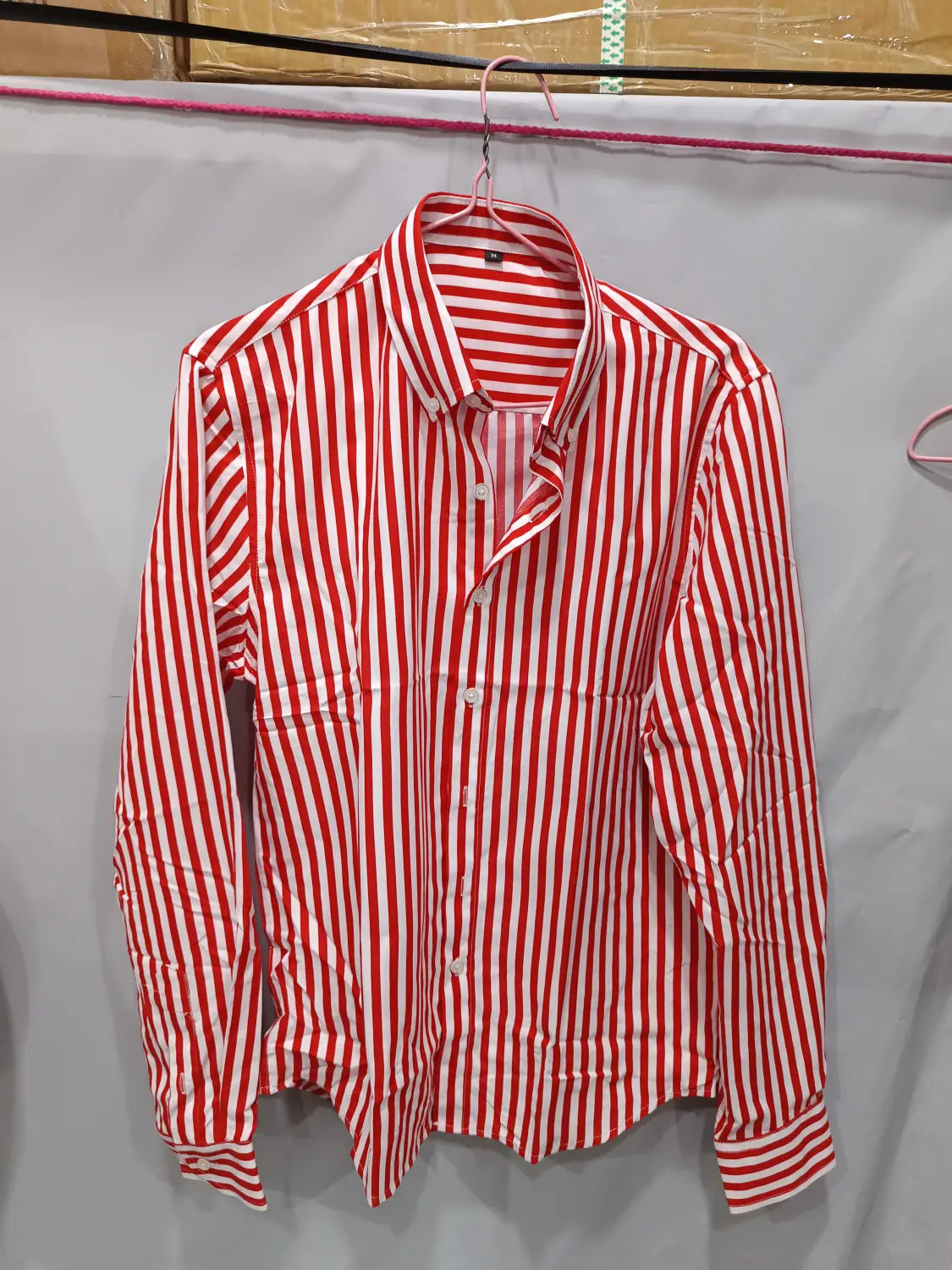 Herren gestreiftes Slim-Fit-Langarm-Freizeithemd in rot-weißen vertikalen Streifen, das an einem Bügel hängt.