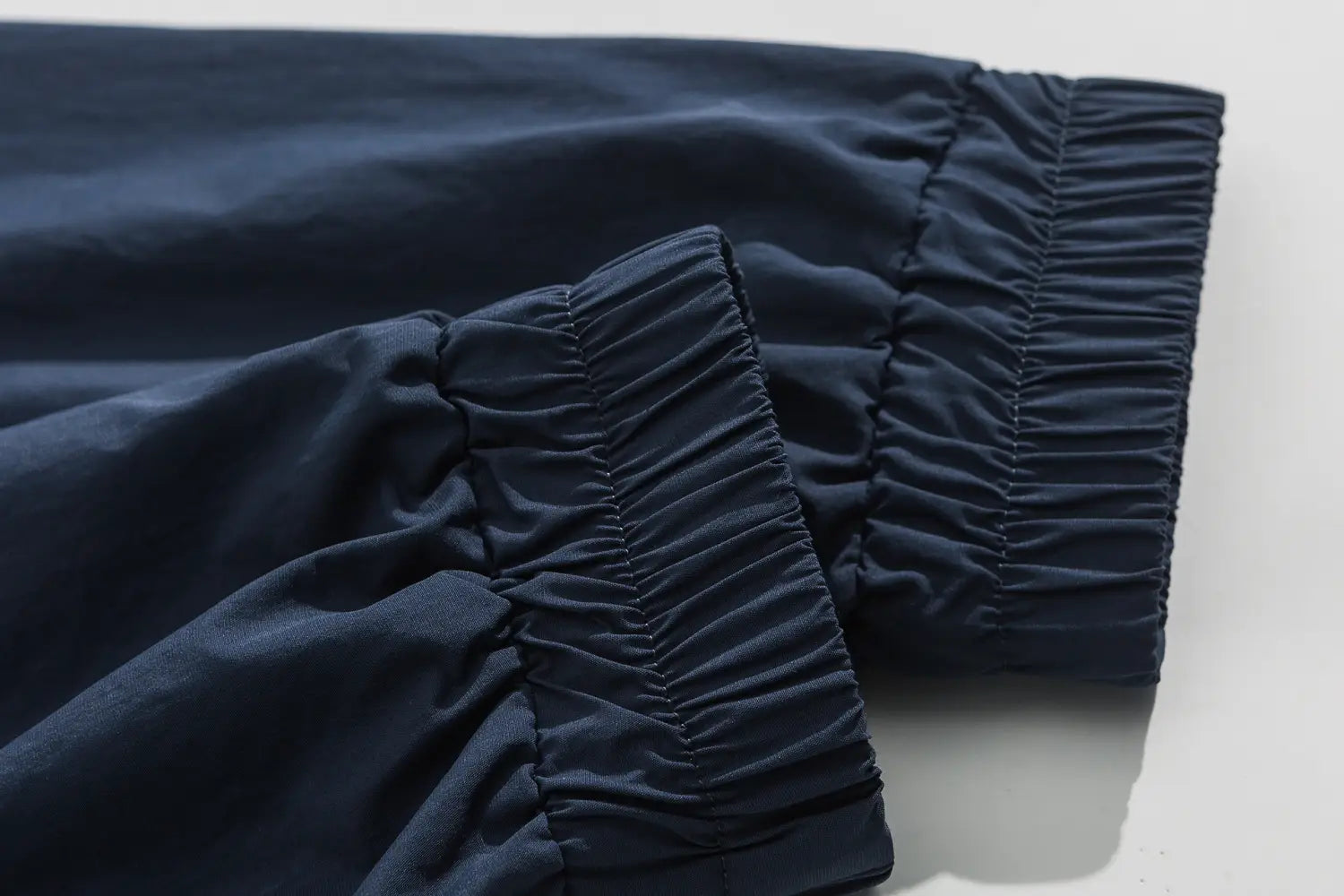 Pantalon bleu marine foncé ample à taille élastique, finition de tissu lisse, assorti à une veste coupe-vent ample à blocs de couleurs brodés.
