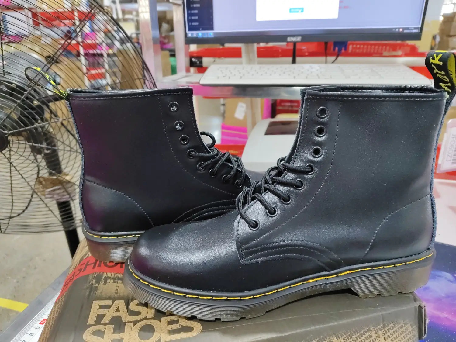 Black leather martin boots featuring yellow stitching shown from the back side.