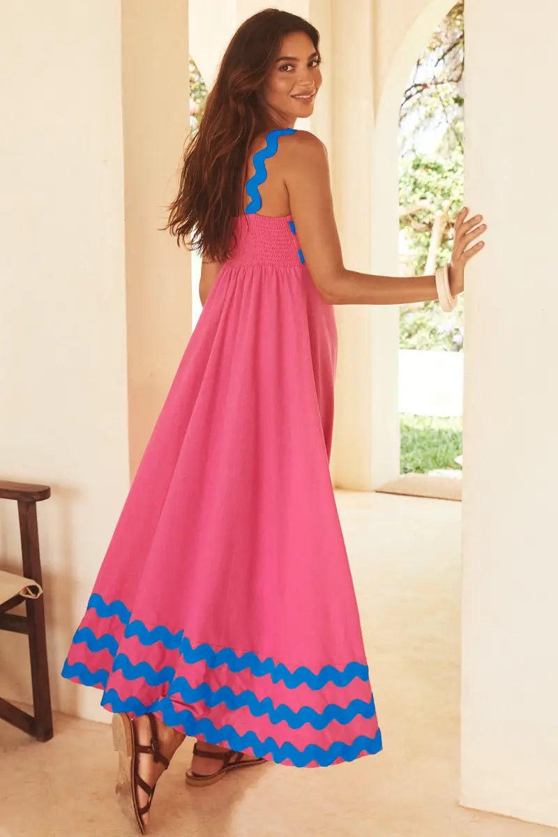 Un vibrante vestido maxi de playa floral con dobladillo ondulado, corte A, rosa, con cuerpo fruncido (smocking) y ribete ondulado azul a lo largo del escote y el bajo.