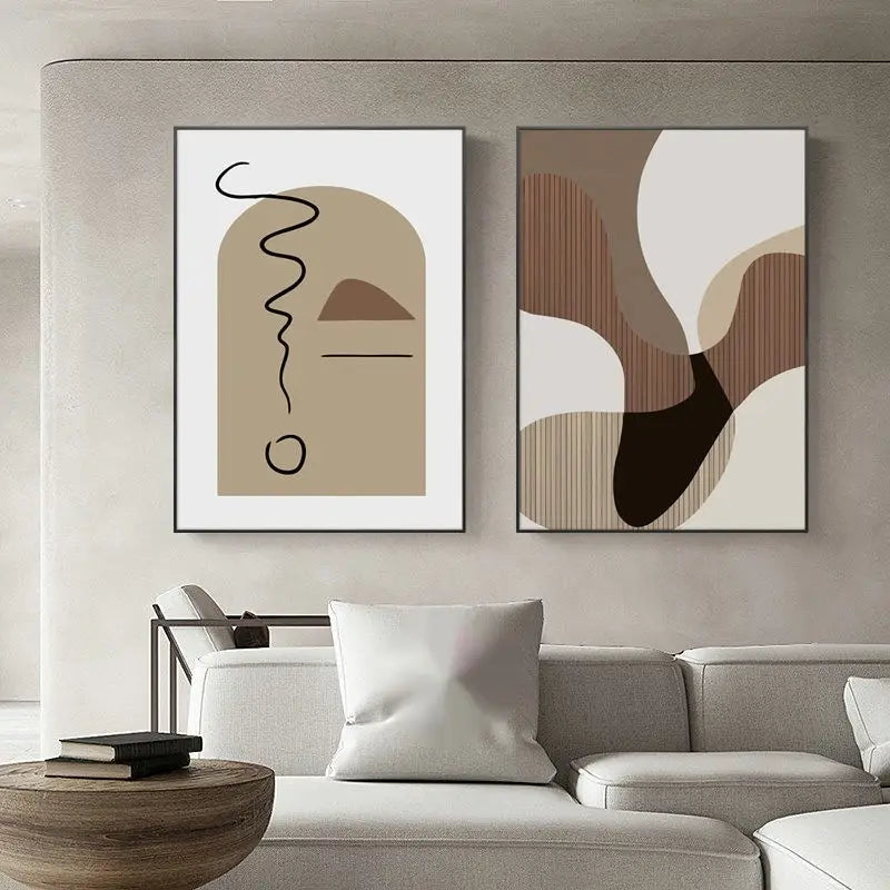 Zwei minimalistische abstrakte Wandkunst-Canvas-Druckbilder mit erdigem beigen, braunem und schwarzem geometrischem Design in dünnen schwarzen Rahmen über einem grauen Sofa.