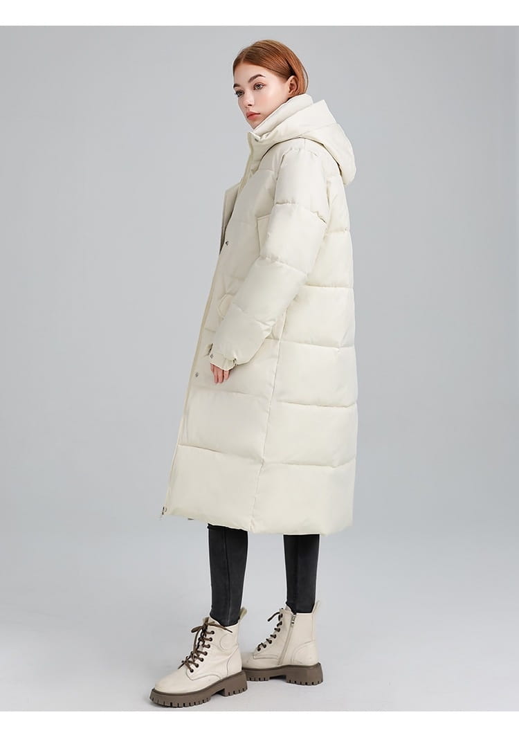 Manteau long matelassé à capuche pour femmes de couleur crème, en matériau matelassé, avec une fermeture éclair à l’avant et une capuche.