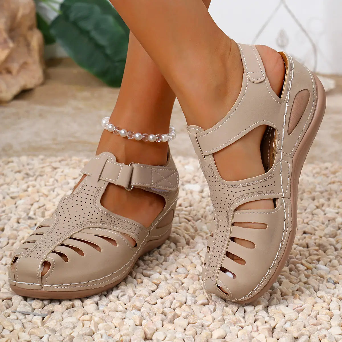 Sandales compensées en cuir beige perforé pour femmes, avec une bride réglable et une surpiqûre décorative, idéales pour des chaussures d’été au style romain.