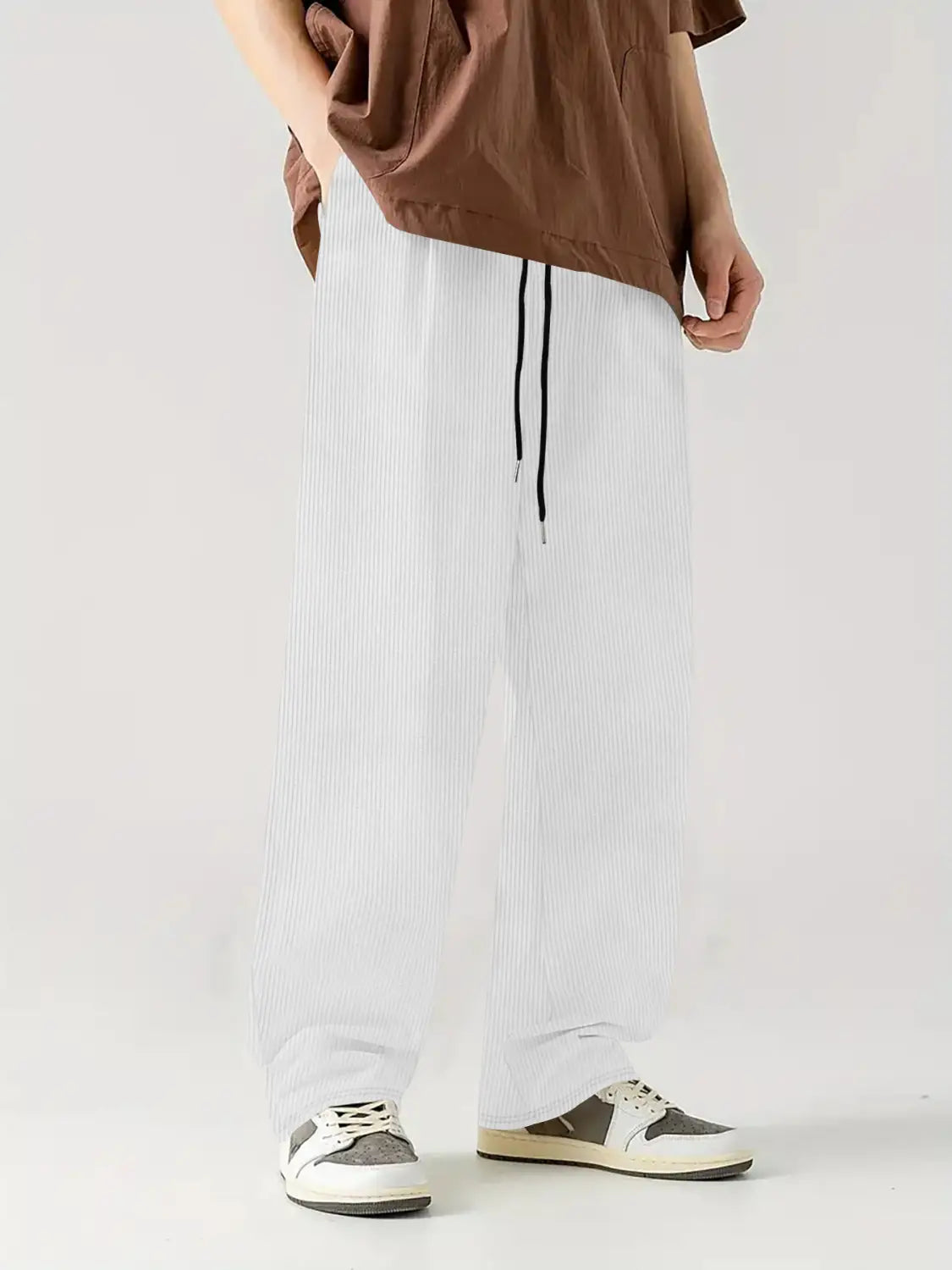 Pantalones casuales rectos de pana blancos con rayas verticales y cordones negros.