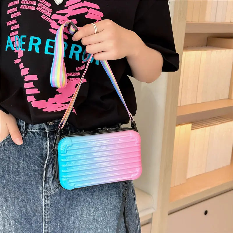Pastel gradient pink and blue mini suitcase crossbody bag with a rainbow-striped strap designed for casual use.