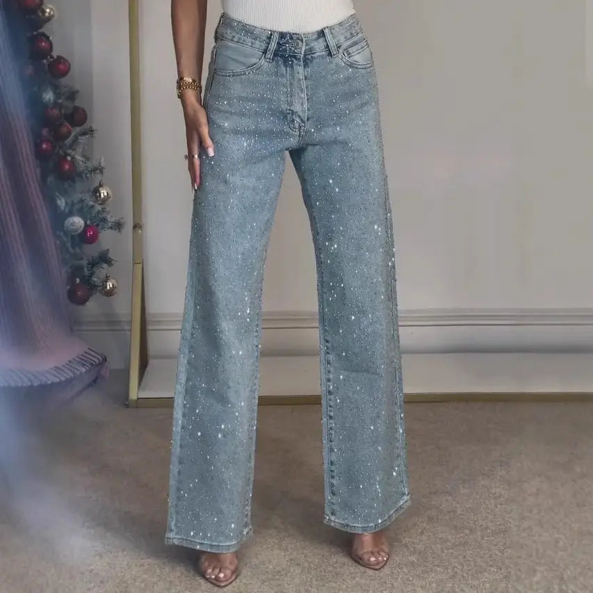 Jeans en denim taille haute à imprimé d’étoiles en denim délavé, avec une coupe à jambes larges et des accents de paillettes argentées étincelantes le long des jambes.
