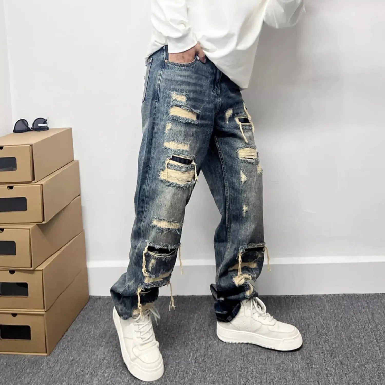 Men’s light blue distressed ripped patch denim jeans featuring multiple ripped patches and frayed edges.