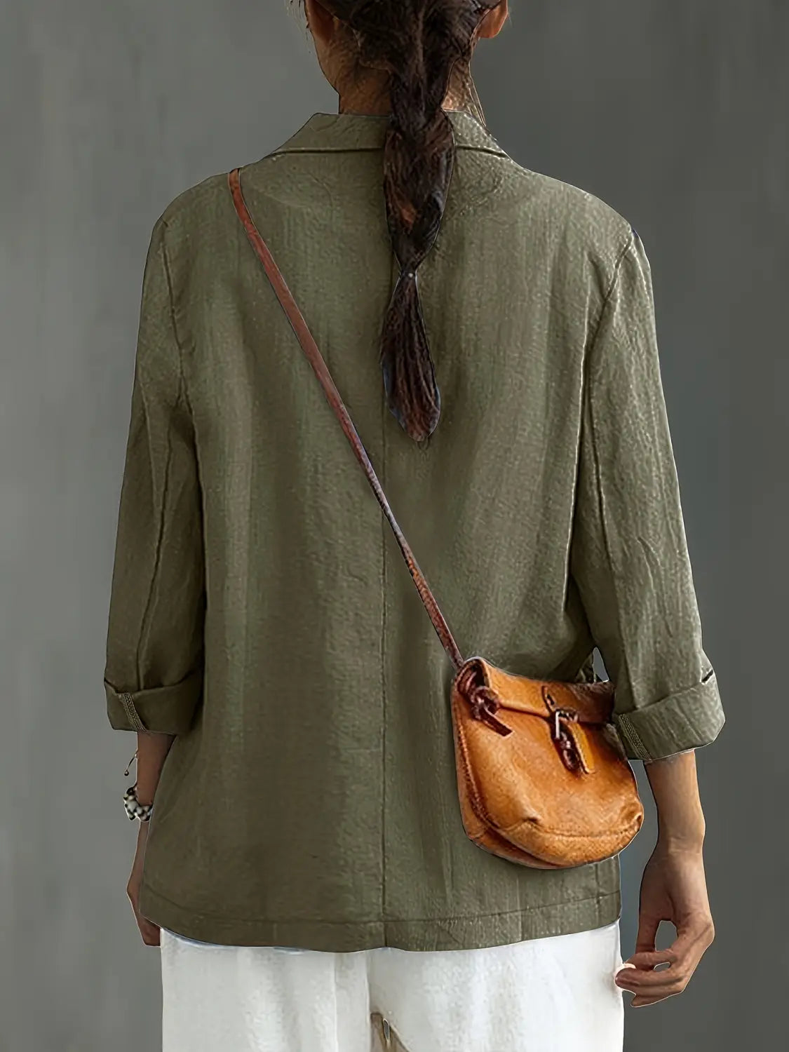 Un bolso cruzado de cuero color camel con cierre de solapa de estilo vintage y correa marrón, combinado con un blazer de lino para mujer, casual y de trabajo.