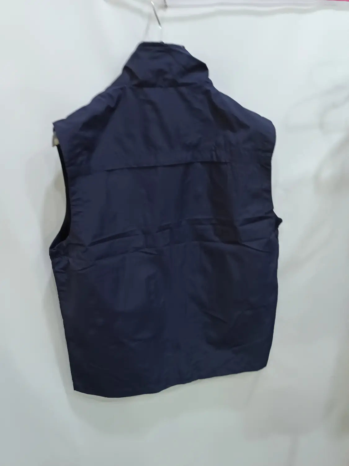 Chaleco utilitario con capucha sin mangas para hombre en azul marino oscuro, con cuello alto y detalles visibles de costura, diseñado para una funcionalidad de múltiples bolsillos.
