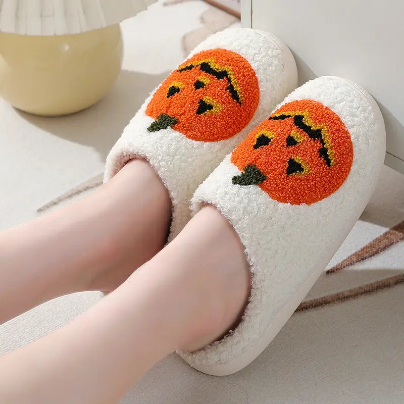 White plush jack-o-lantern embroidered halloween slippers featuring orange pumpkin faces with black and yellow details.