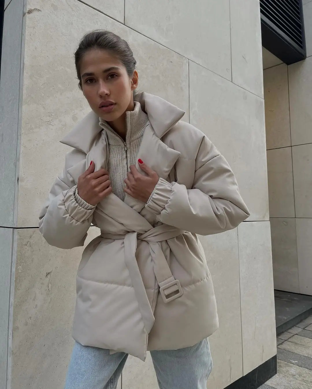 Beige Damen-Gurtsteppjacke mit Kapuze, wattierte Pufferjacke mit gerippten Bündchen, für Winterbekleidung konzipiert.