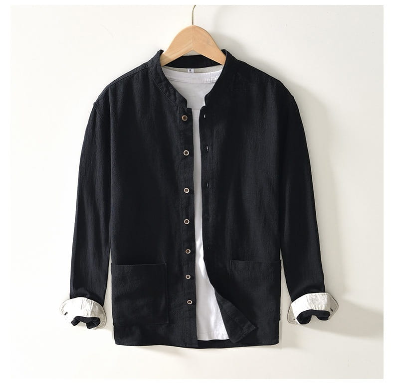 Camisa casual de lino rami para caballero en color negro, de manga larga, con cuello mandarina y puños blancos colgando de una percha de madera.