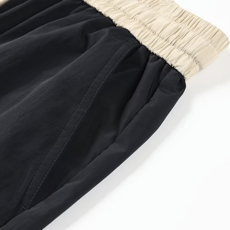Shorts en nylon décontractés pour hommes, coupe droite, noirs, avec une taille élastique, une ceinture côtelée beige et des détails de coutures discrets.