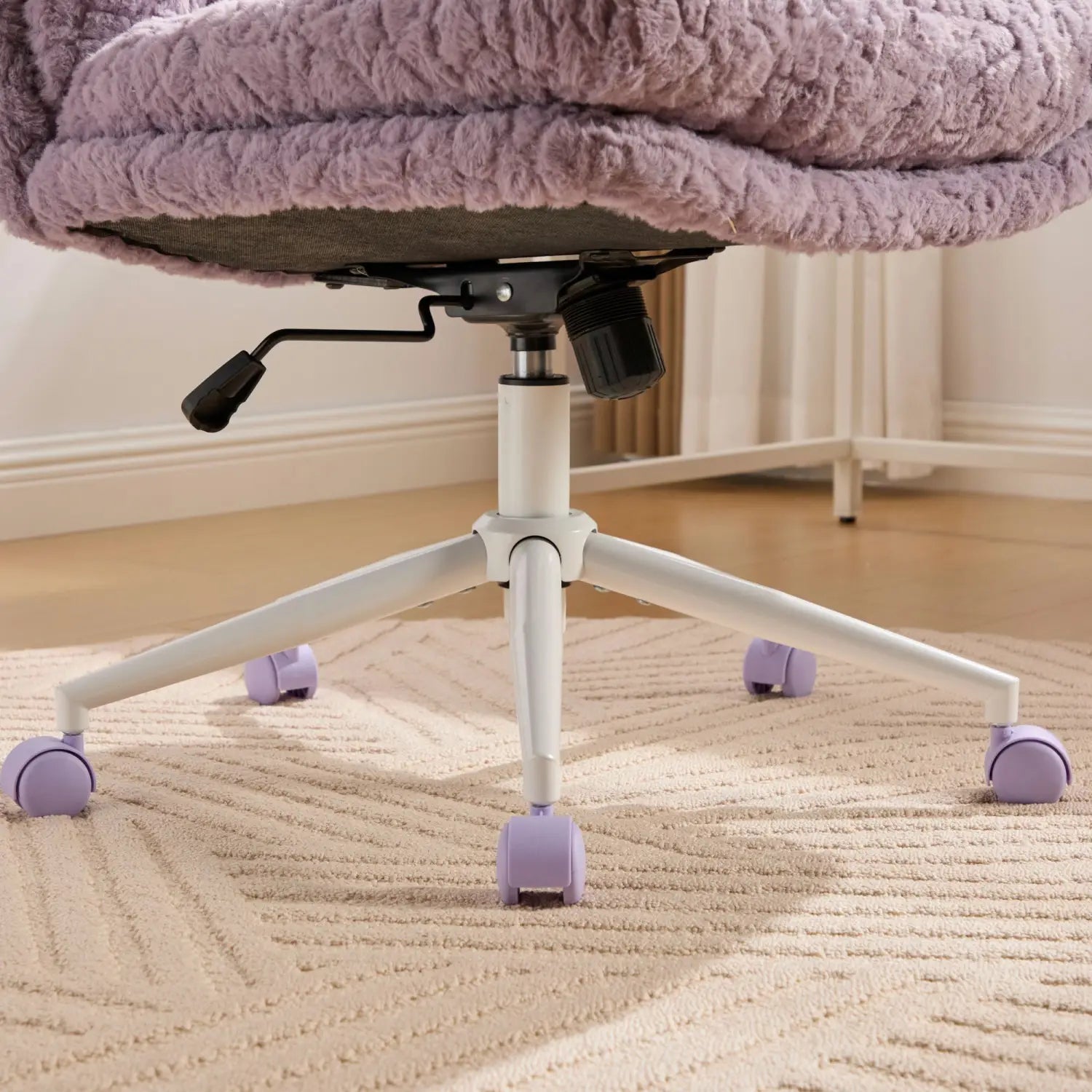 Un fauteuil de bureau moelleux en fausse fourrure violette couleur lavande, avec une assise de 26,4 pouces de largeur, un tissu duveteux texturé et des roues à roulettes violettes assorties sur une base en métal blanc.