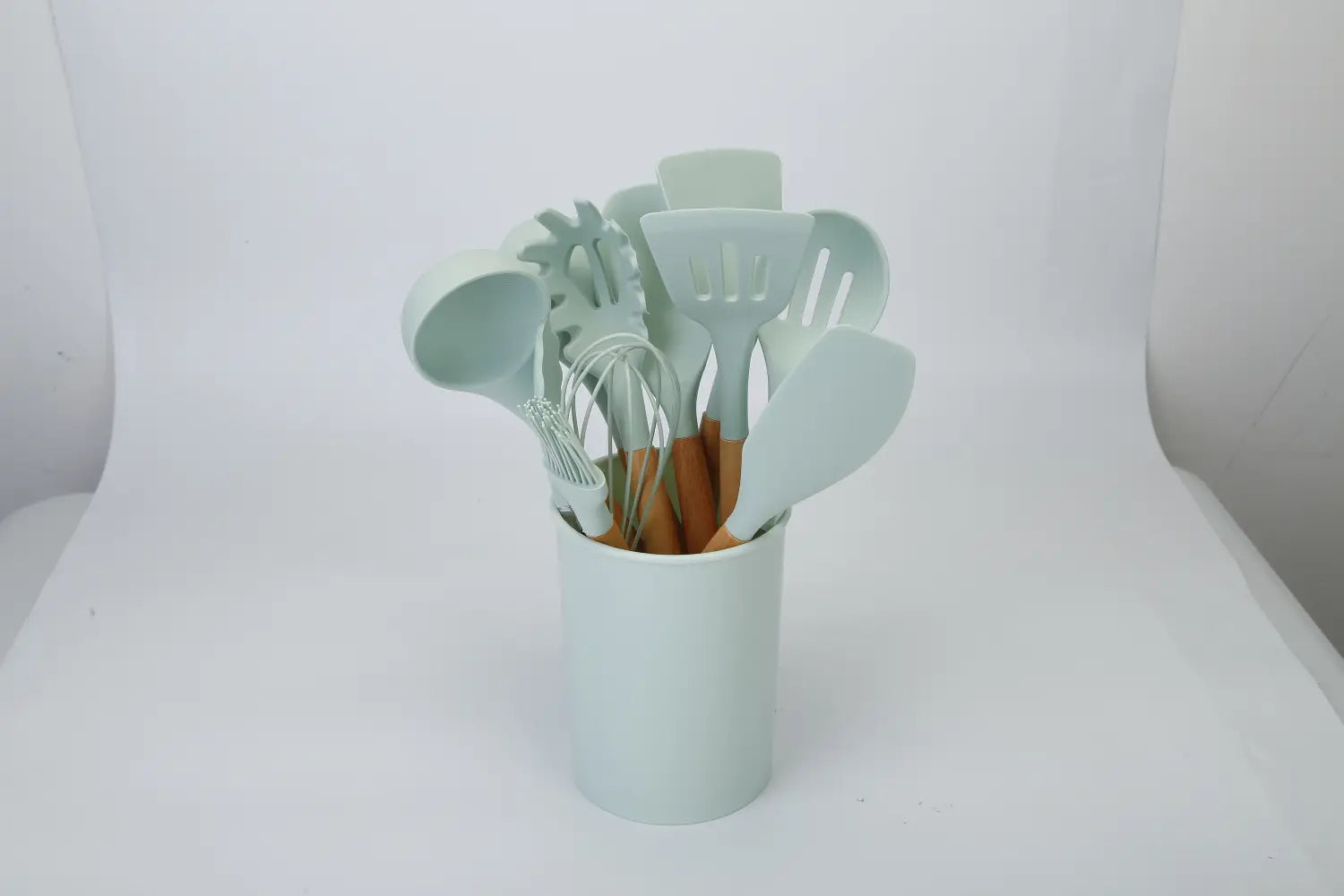 A set of 11 light blue silicone cooking utensils with wooden handles neatly arranged in a matching cylindrical container.