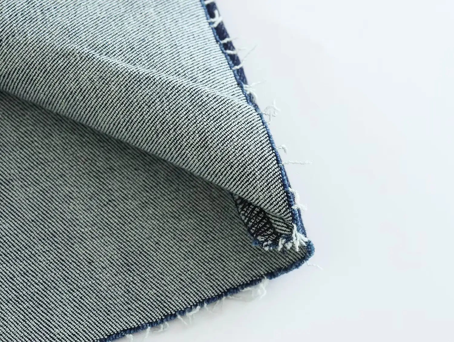 a close-up of faded blue denim fabric with visible stitching and frayed edges paired with a high neck navy velvet zip front maxi dress showcasing mixed textures and materials