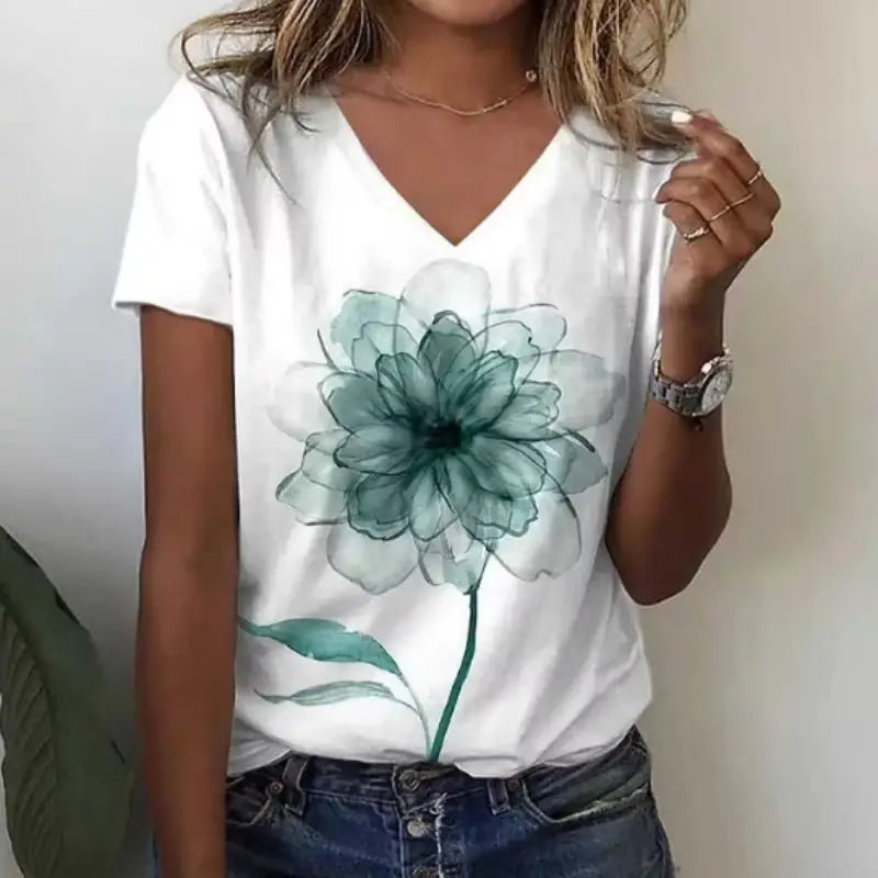 Camiseta blanca de cuello en V con un gran estampado floral translúcido en color teal con delicados pétalos y hojas estilo acuarela, denominada camiseta de cuello en V floral de acuarela.
