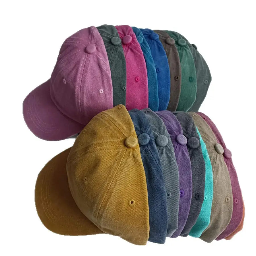 A collection of colorful vintage washed cotton corduroy baseball caps in pink blue green and mustard yellow designed as sun hats.