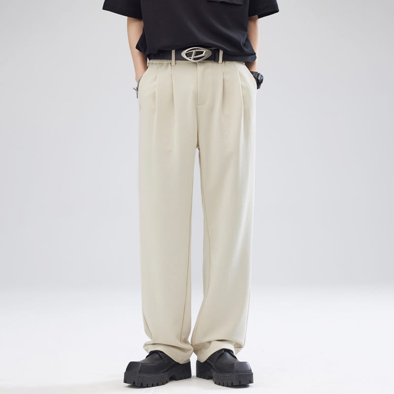 Pantalon pour hommes à plis, coupe ample à jambes larges et ajustement décontracté, couleur beige, confectionné dans un tissu de coupe lisse, avec des coutures verticales nettes.