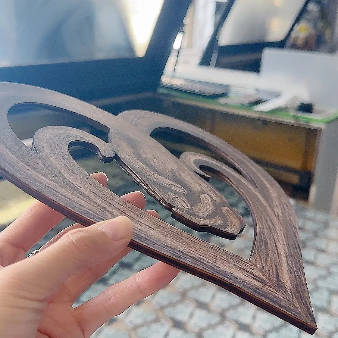 Dunkelbraunes Holz-Dekoschale mit filigranen, sich windenden Ausschnittmustern, dargestellt in einer Skulptur für eine herzförmige Wanddekoration: ineinander verschlungene Hände.