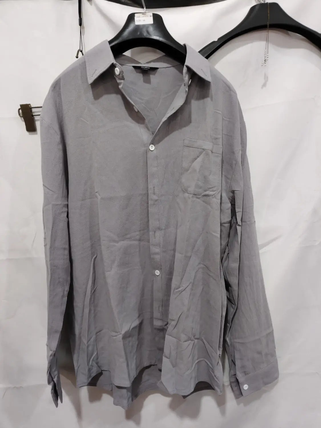 Chemise décontractée en coton et lin gris, à manches longues, avec poche poitrine et boutons blancs.