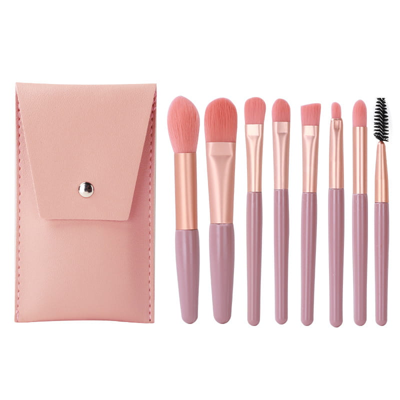 Makeup brush set with eight pieces in pink blush tone and rose gold accents featuring a matching pink leather case.