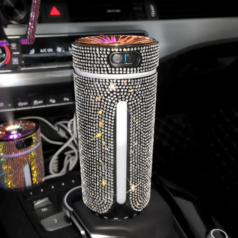 Ein funkelnder, silberner mit Strasssteinen verzierter USB-Autoluftauffrischer und -befeuchter mit einer leuchtenden Oberseite und einem eleganten zylindrischen Design.