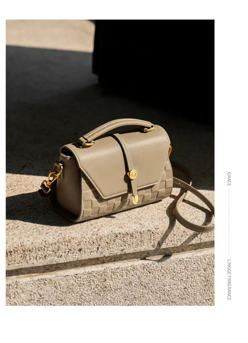Beige zweifarbige Webleder-Crossbody-Handtasche mit goldtönigen Beschlägen und einem oberen Henkel.