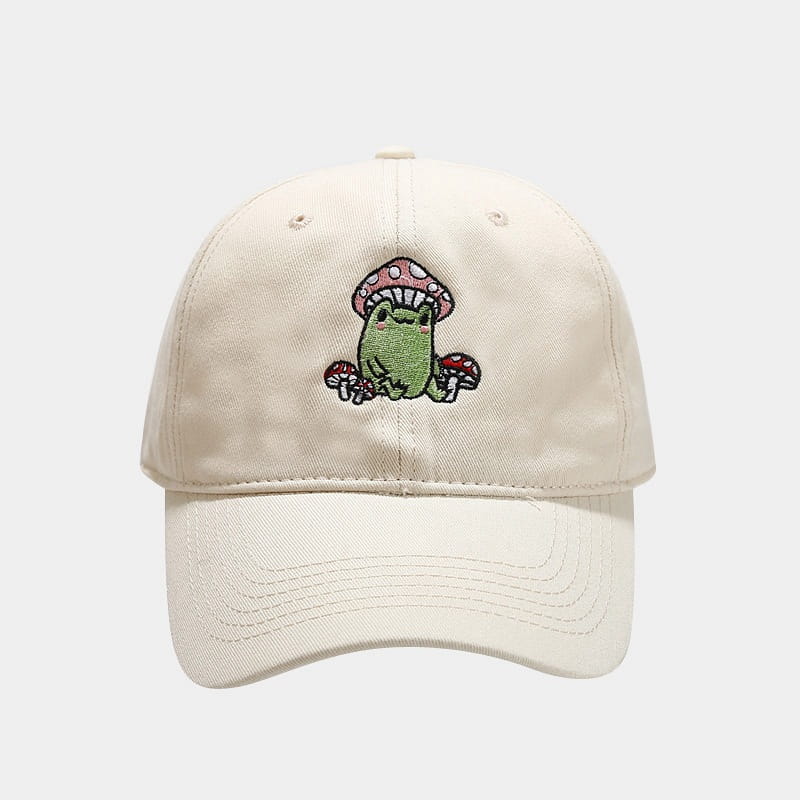 Cream-colored baseball cap made of fabric featuring a charming embroidered design of a green frog with pink and white polka-dotted mushrooms titled Frog Mushroom Embroidered Baseball Cap.