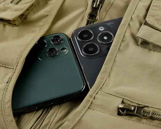 Deux smartphones en vert foncé et en noir reposent côte à côte à l’intérieur de la poche du gilet utilitaire en mesh à séchage rapide de couleur kaki pour hommes