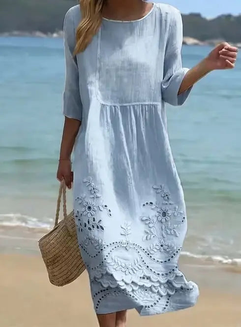 A light blue linen embroidered umbrella dress featuring delicate white floral embroidery and a scalloped hem.