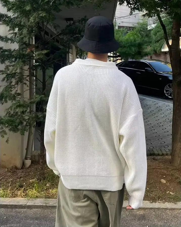 A cream-colored ribbed knit men long sleeve polo sweater with a relaxed fit and a collar.