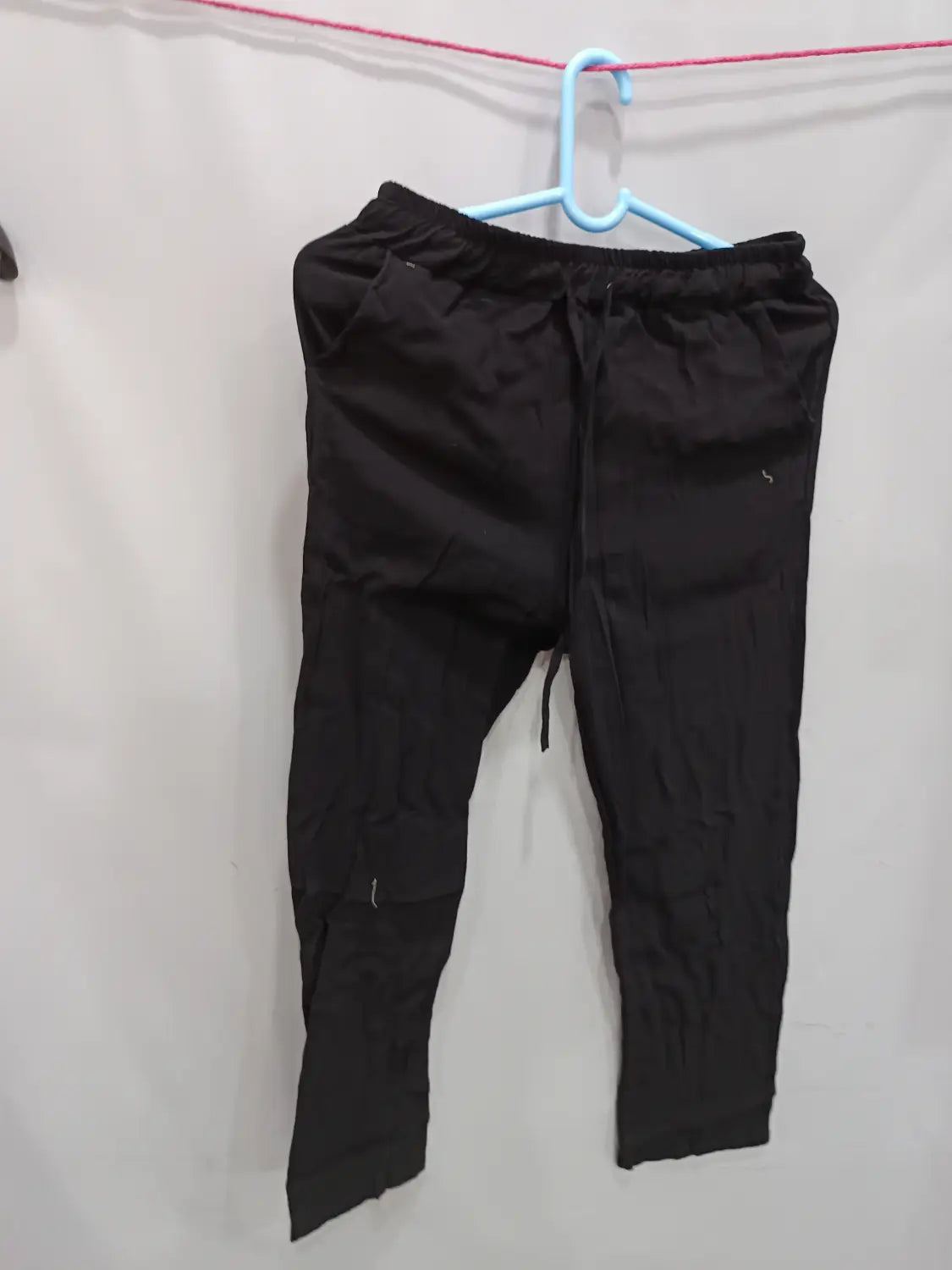 black linen men’s joggers casual summer drawstring trousers hanging on a blue hanger