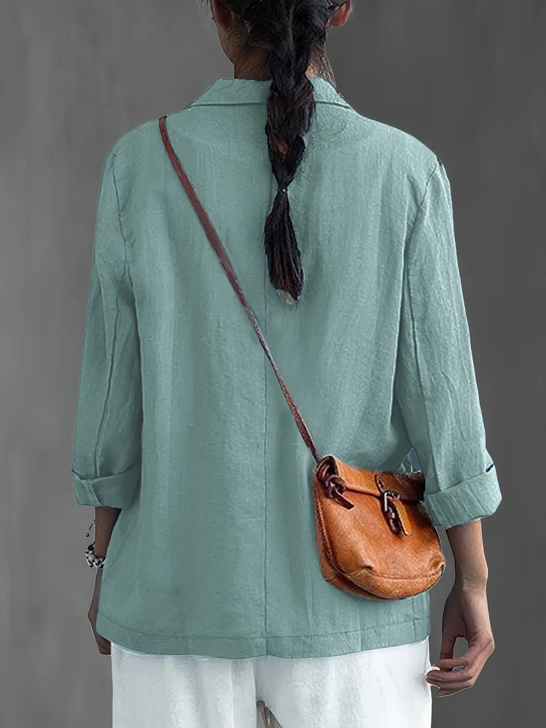 Un bolso cruzado de cuero color camel con cierre de hebilla y correa marrón, combinado con un blazer de lino para mujer, casual y de trabajo.