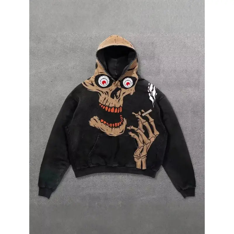 Sweat à capuche oversize de style streetwear à imprimé graphique rétro 3D pour hommes, de couleur noire, arborant un crâne beige avec des yeux rouges et des dents orange, tenant une cigarette dans sa main squelettique.