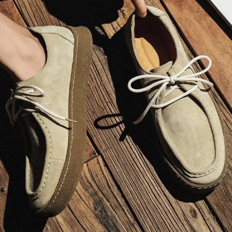 Beige suede British style casual lace up leather shoes with white laces and a brown rubber sole.