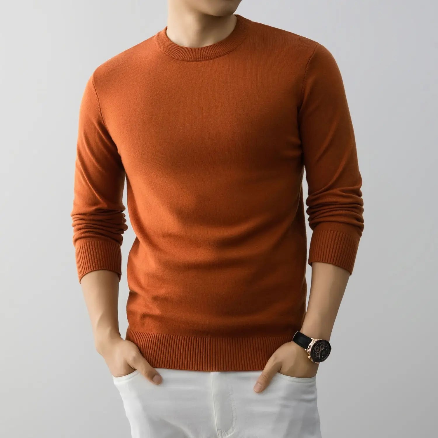 Ein Herren-Minimalist-Pullover mit Rundhalsausschnitt aus Strick in rost-orange, gefertigt aus weichem Strickmaterial, mit gerippten Bündchen und Saum.