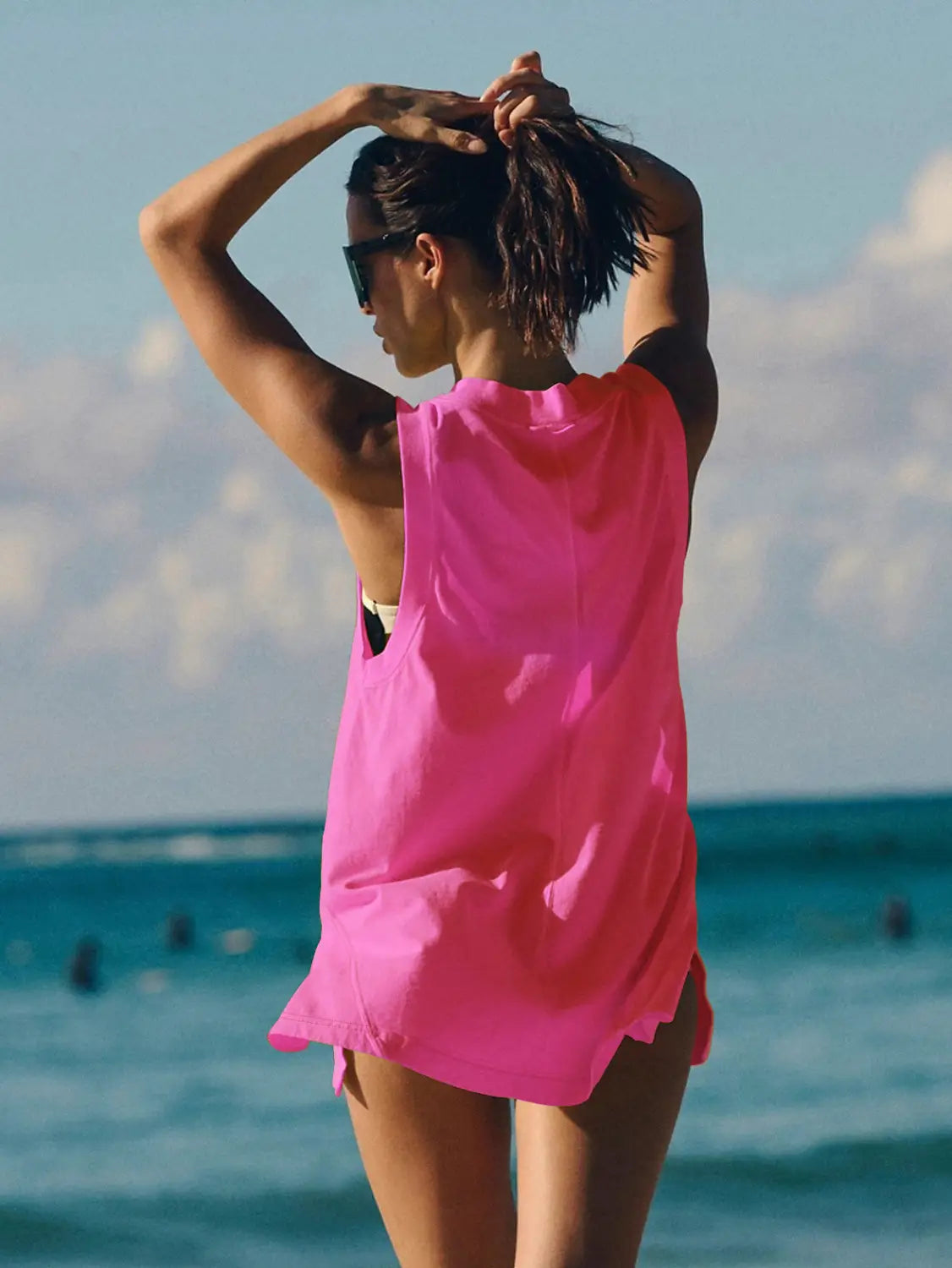 A vibrant pink sleeveless cotton wrap vest top with a relaxed v neck and flowing fabric featuring an asymmetrical hemline.