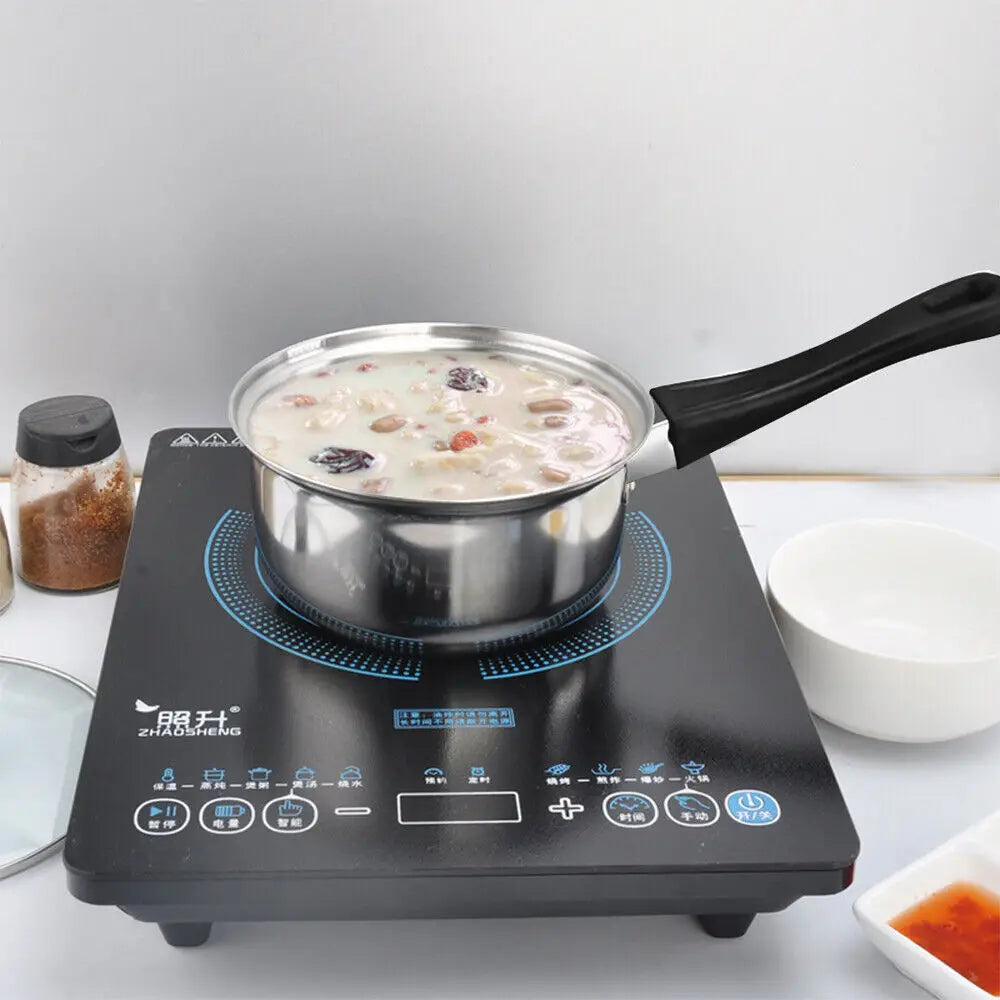 Black induction cooktop with a silver stainless steel pot from a 12 piece cookware set with glass lids.