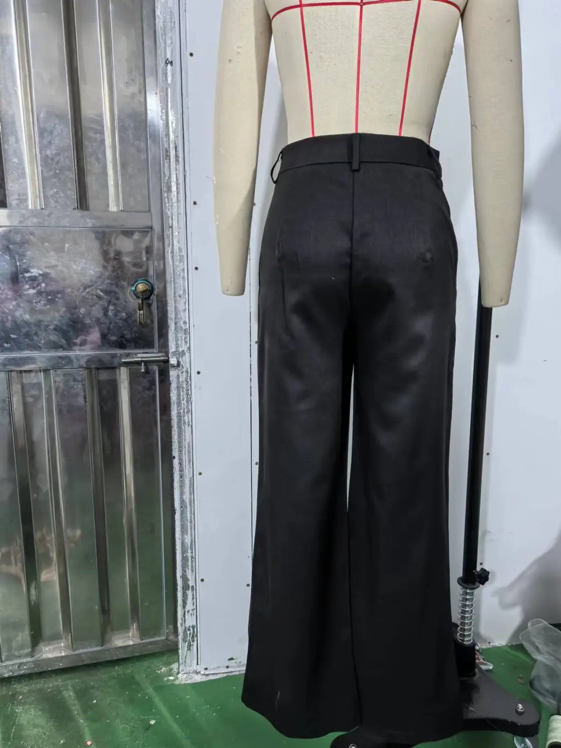 Schwarze asymmetrische Weitbein-Hosen aus einem glatten, leicht glänzenden Stoff mit geradem Schnitt.